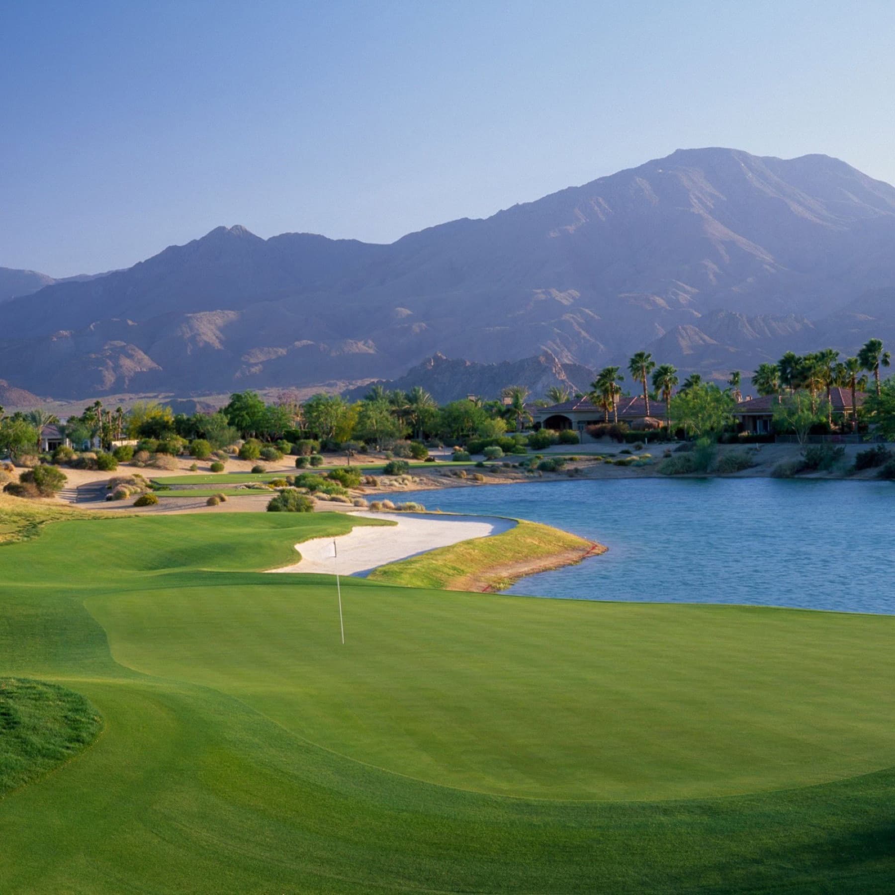 A Greg Norman Course green on the water's edge under the Santa Rosas