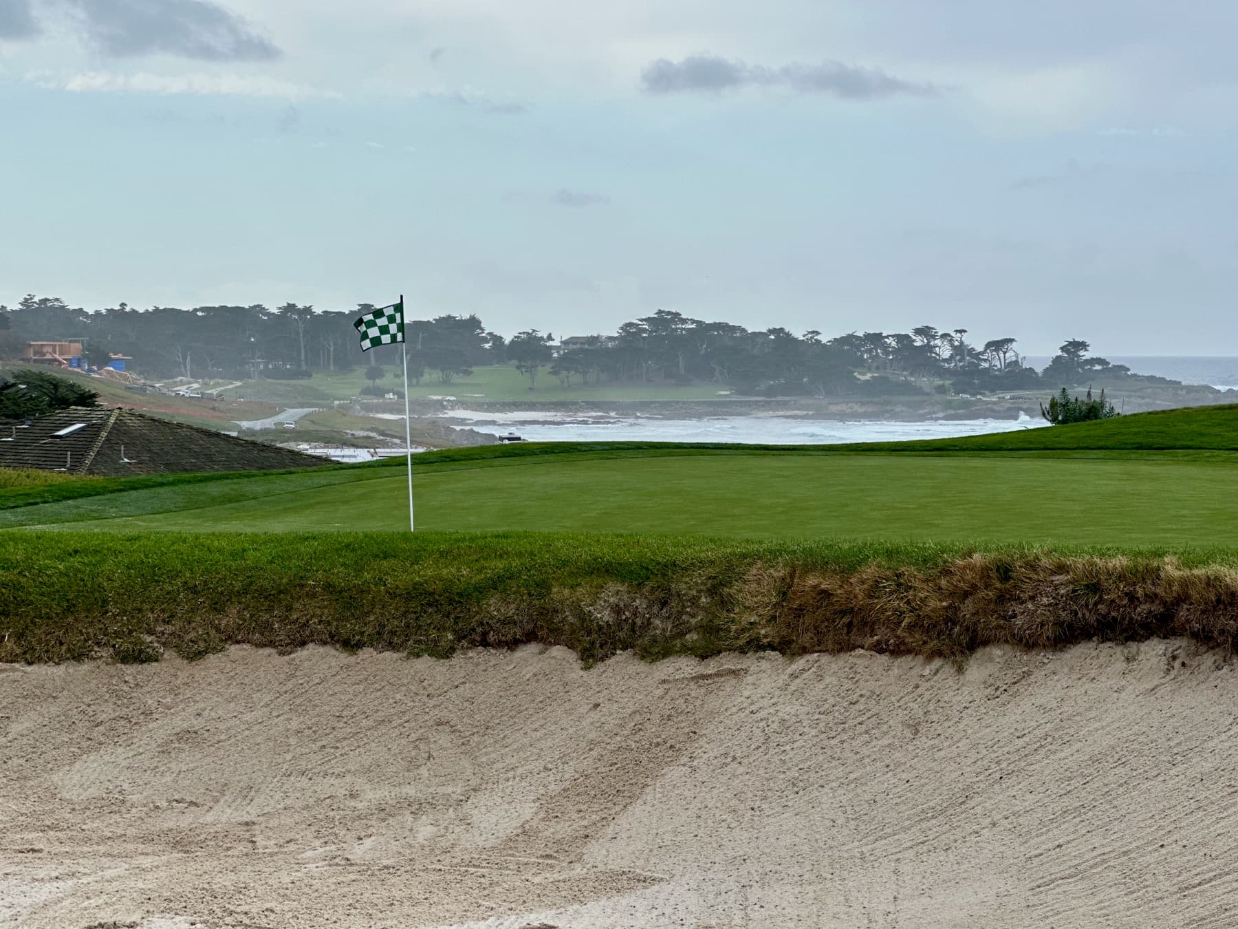 a Spyglass Hill green above Carmel Bay, the Pacific breaking beyond