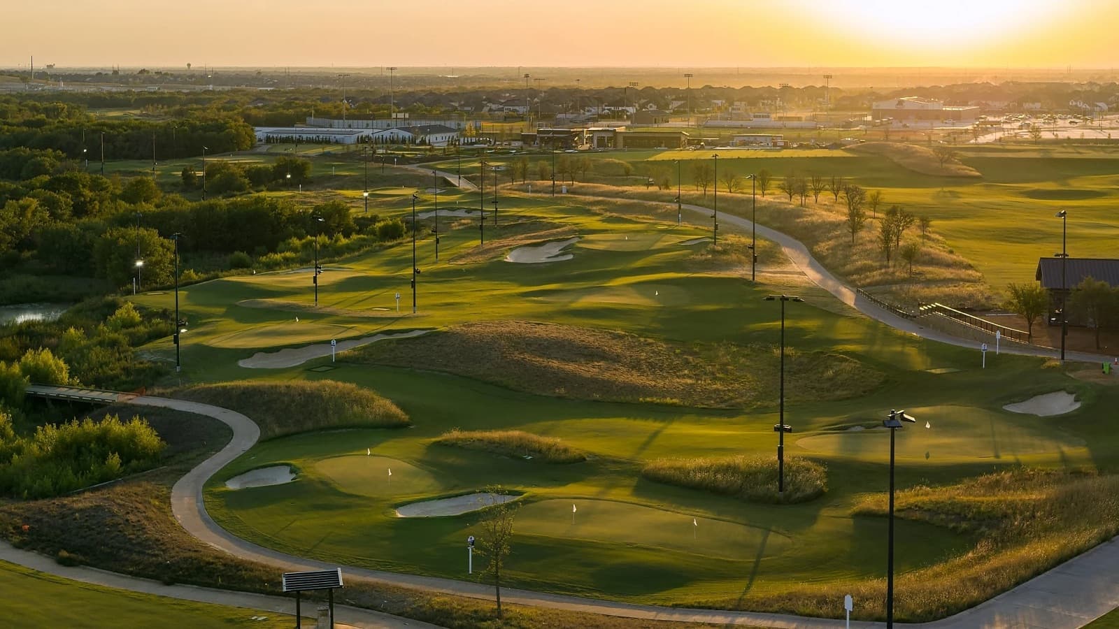 The Swing's par-3 greens at sunset, lit for night play